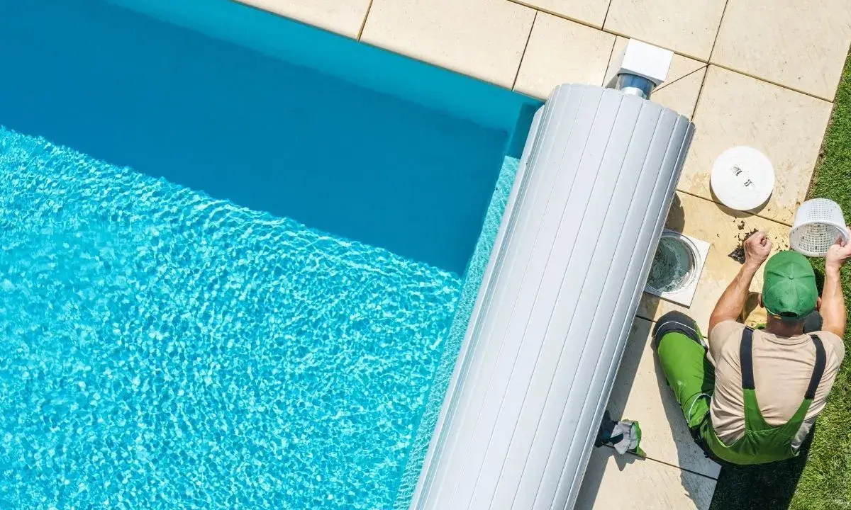 Un technicien nettoie le filtre de la pompe de piscine, un entretien essentiel pour optimiser la consommation d'énergie.