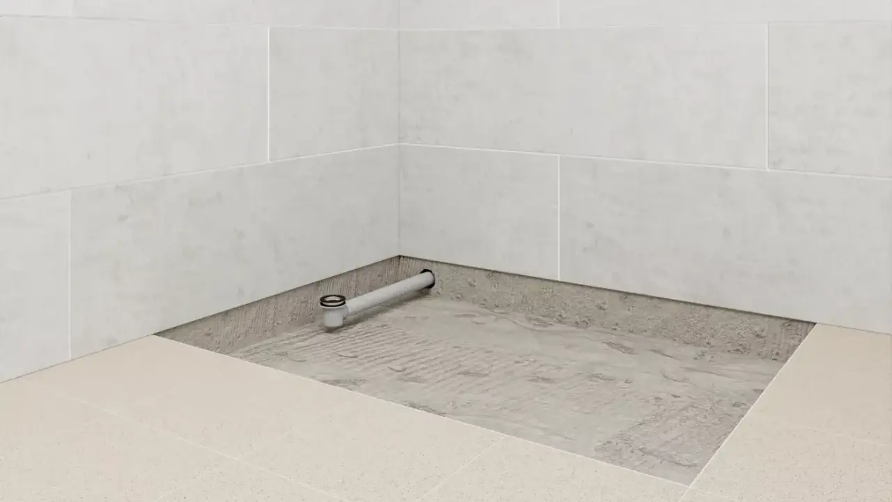 Installation d'un receveur de douche : un siphon est posé sur une chape avant le carrelage.