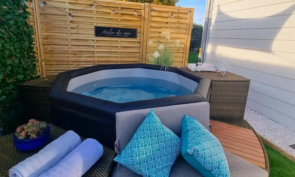 Ambiance relaxante autour d'un spa gonflable : coussins bleus, serviettes douces et guirlande lumineuse pour une deco parfaite.