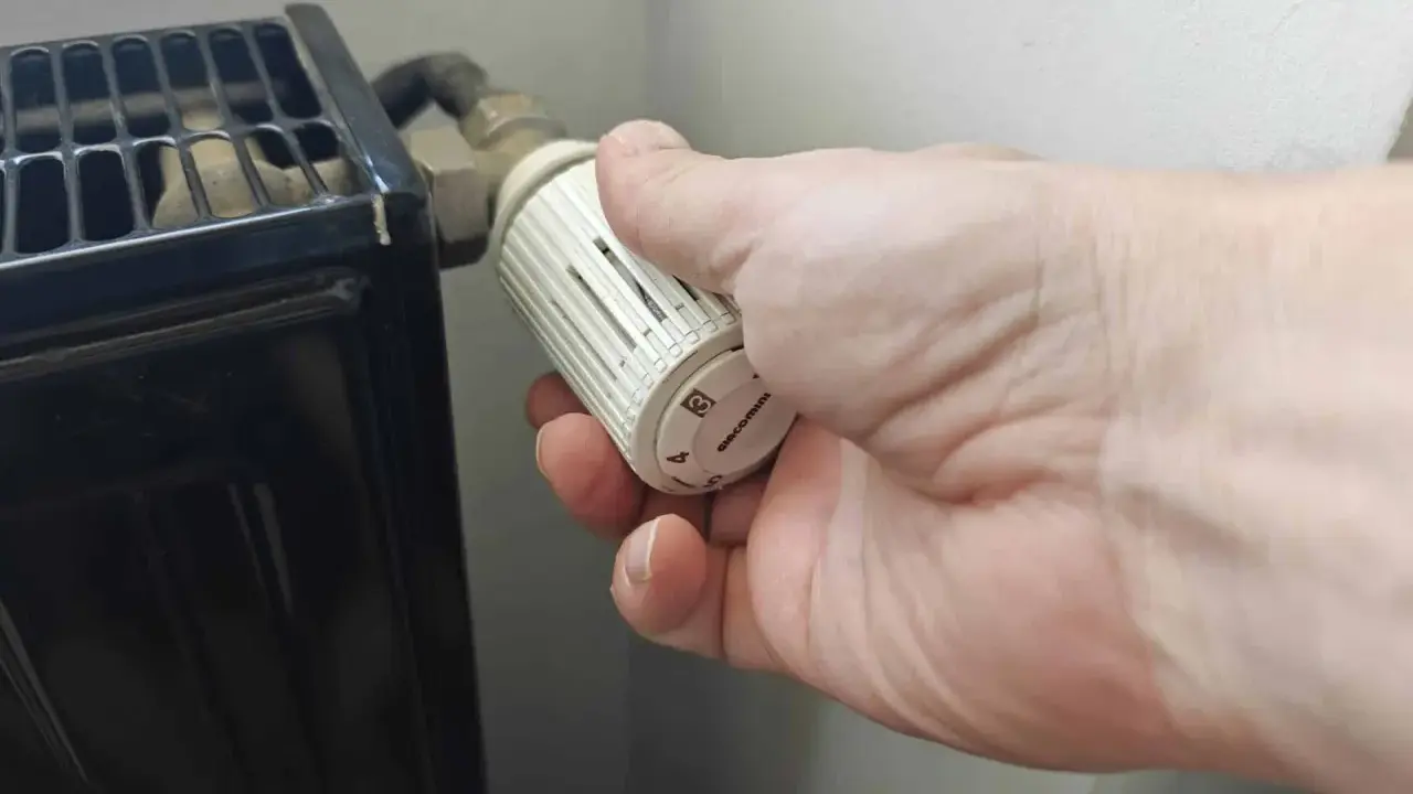 Main tenant ajuste le thermostat pour savoir quand éteindre le chauffage.