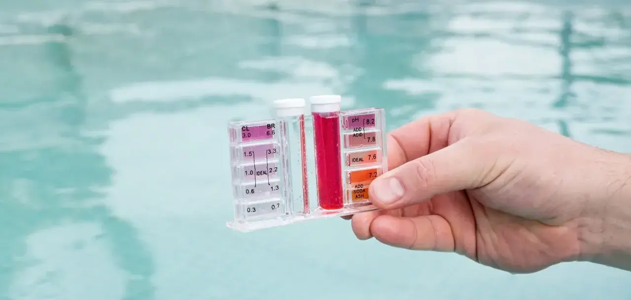 Testeur de piscine mesurant le chlore et le pH. La couleur rouge indique un niveau de chlore élevé, suggérant qu'il faut enlever le chlore de l'eau.