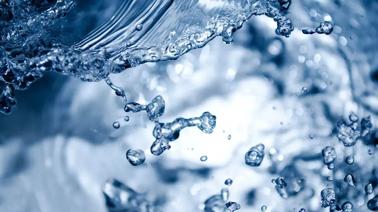 Éclaboussures d'eau bleue, évoquant la dureté de l'eau à Rennes. Des gouttelettes figées dans l'air, capturant le mouvement dynamique.