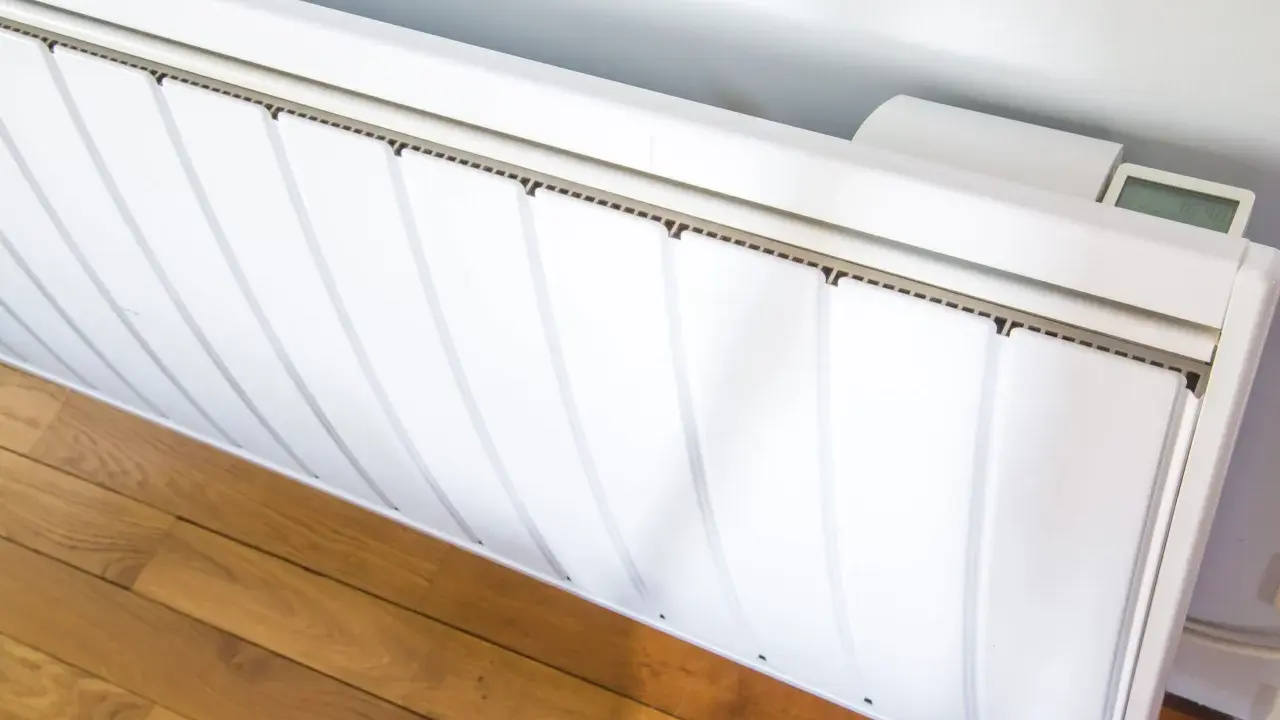 Radiateur électrique blanc installé sur un parquet. Un écran affiche la température. Guide pour comment installer un radiateur électrique.