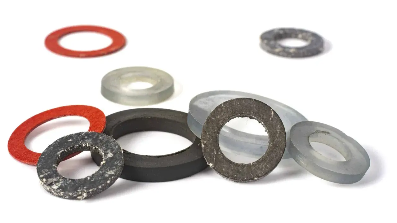 Ensemble de rondelles de différentes tailles et couleurs, dont un joint moulé rouge, gris et noir, sur fond blanc.