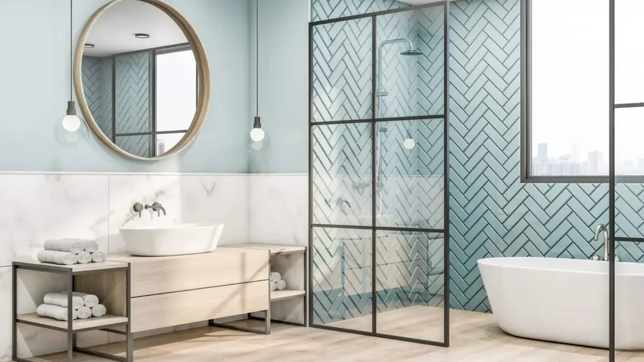 Salle de bain moderne avec baignoire, douche et lavabo. Le mur de la douche est décoré de carreaux bleu sarcelle posés en chevrons.
