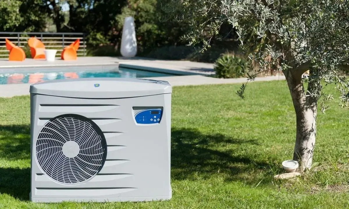 Pompe à chaleur pour piscine, élément clé d'un schéma de filtration performant, installée sur une pelouse verdoyante près d'une piscine.