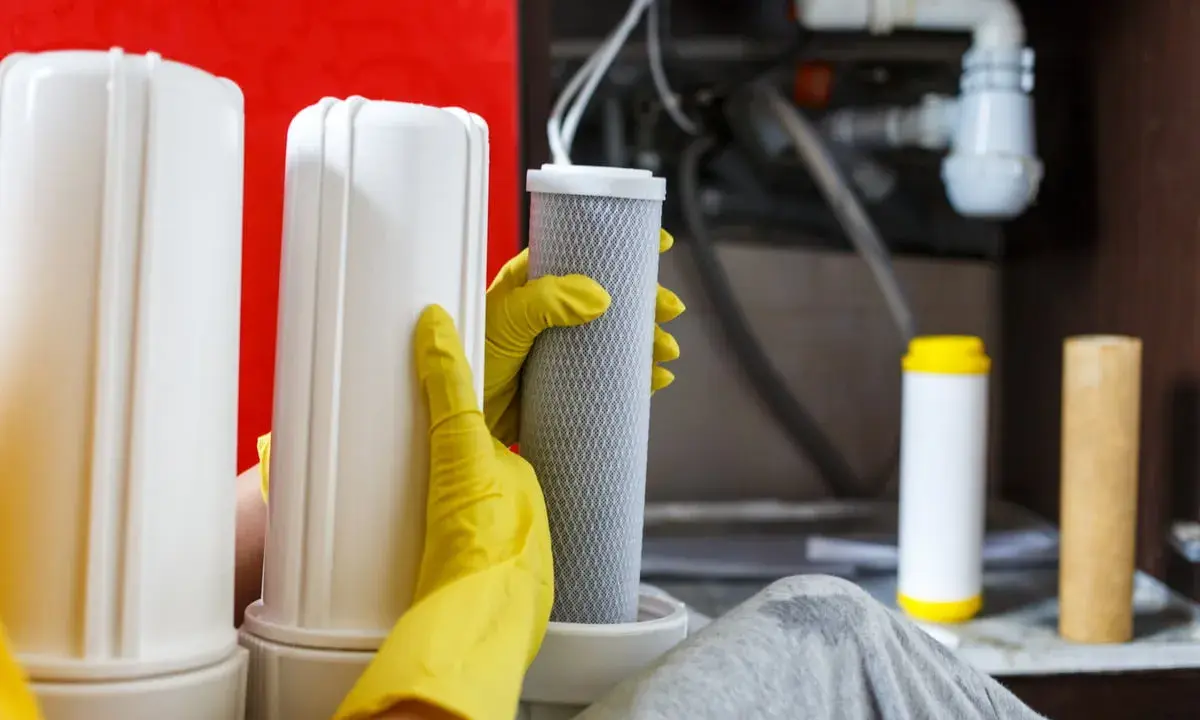Mains de gant jaune manipulant un filtre pour le nettoyage résine adoucisseur d'eau.