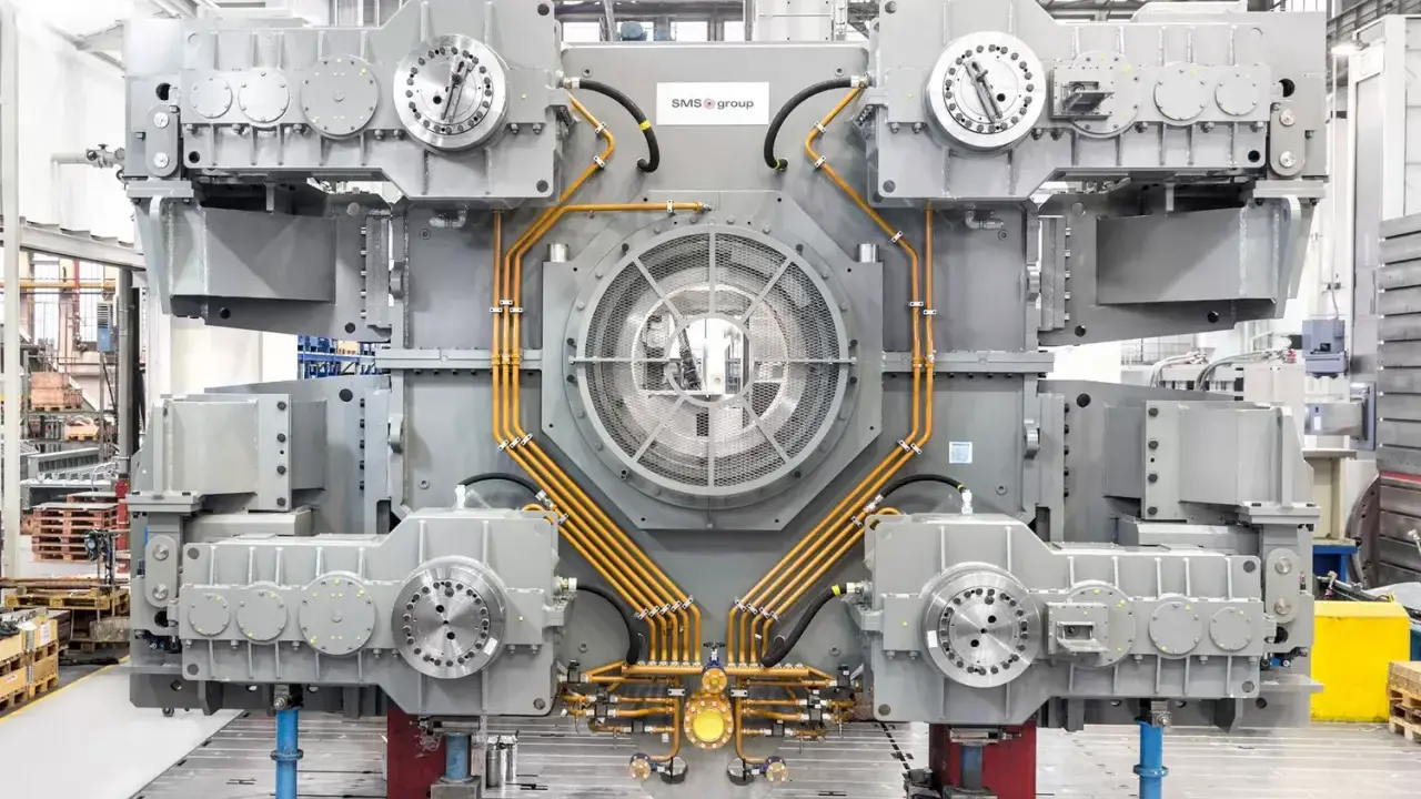 Gros équipement industriel gris avec des tuyaux orange, un ventilateur central et des éléments circulaires. Il s'agit d'un joint SMS, prêt pour l'assemblage.