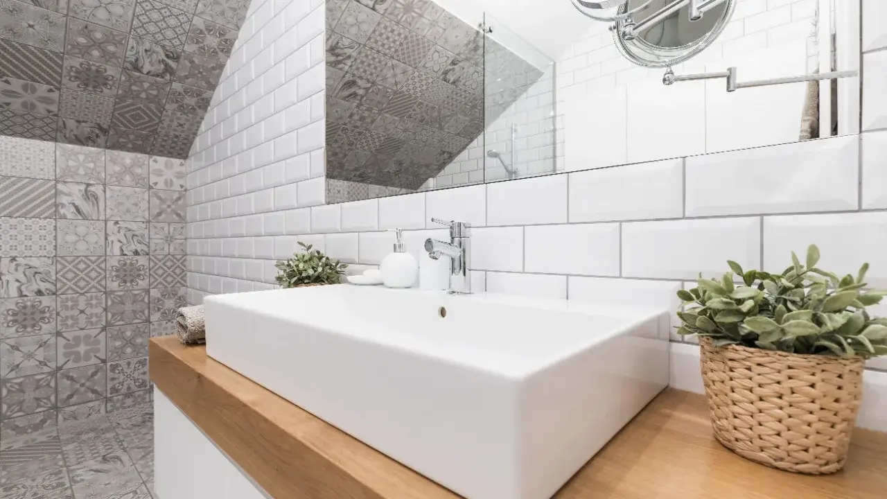 Salle de bain moderne avec lavabo rectangulaire, robinetterie chromée et un mur orné de carreaux de métro blancs et de motifs géométriques. Le **pose carrelage mural** crée un contraste saisissant.