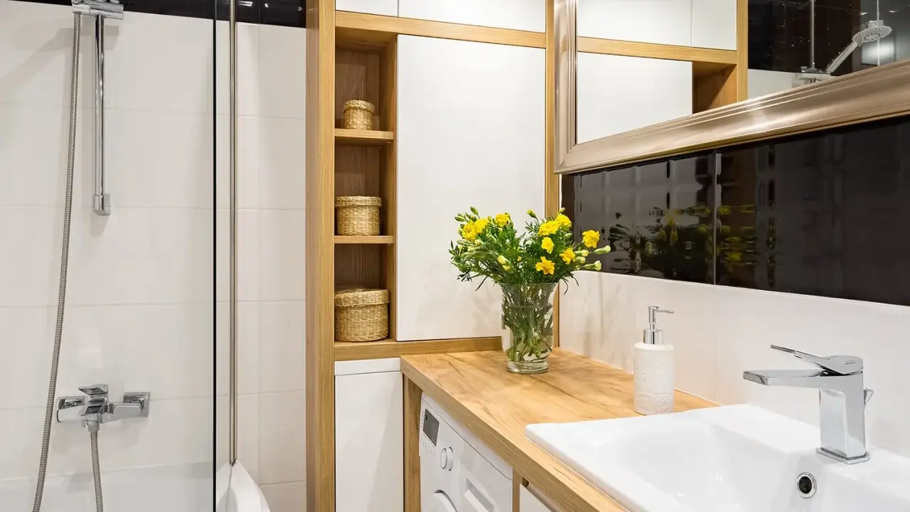 Une petite salle de bain moderne avec une douche, un lavabo, une machine à laver et des paniers en osier sur des étagères en bois.