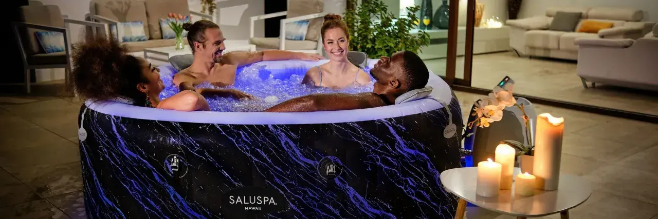 Quatre amis profitent d'un moment de détente dans un spa gonflable, illuminé de bleu. L'entretien de ce spa gonflable est simple pour des moments de pur bonheur.