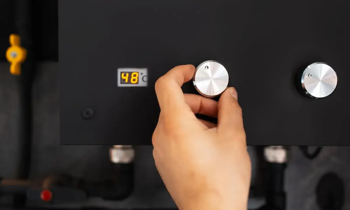 Main d'une personne ajustant le bouton d'une pompe à chaleur connectée affichant 48°C.