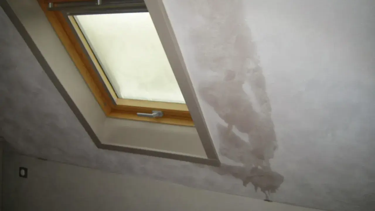 Gouttes d'eau sur le mur d'une maison non chauffée, près d'une fenêtre de toit. La condensation s'accumule et coule.