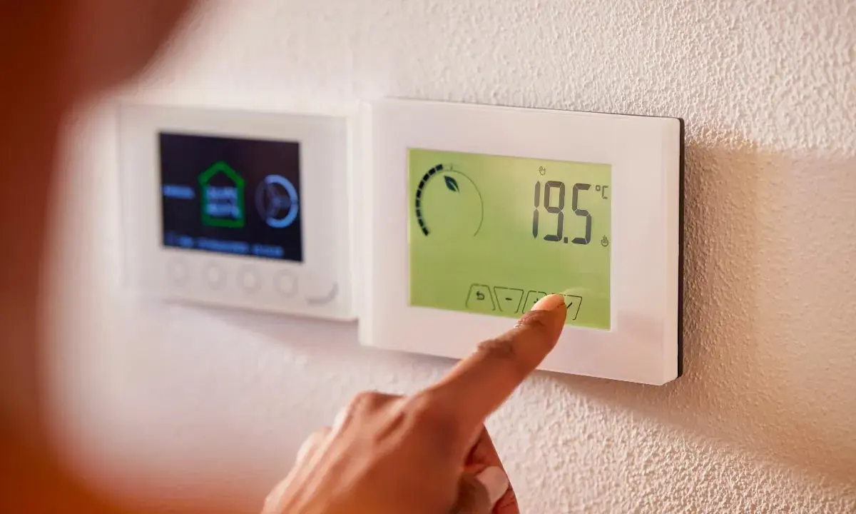 Main d'une personne ajustant un thermostat intelligent, symbole de la domotique sans fil. Confort et efficacité énergétique à portée de main.
