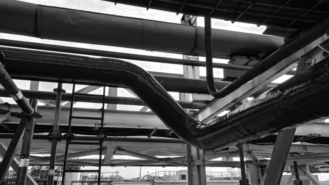 Gros plan sur des tuyaux industriels, certains recouverts d'une texture rugueuse suggérant un colmatage ou une isolation.