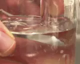 Main d'une personne tenant un verre d'eau potable à Poitiers. L'eau est claire et reflète la lumière.