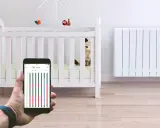 Contrôle du chauffage de la chambre bébé via smartphone. Un radiateur blanc et un lit de bébé sont visibles.