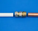 Raccordement de tuyaux : un coude 1/4 mâle femelle en laiton et un tube de cuivre à côté d'un tube blanc.