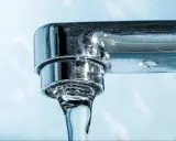 Gouttes d'eau tombant d'un robinet chromé, montrant des dépôts calcaires, un signe du tableau dureté de l'eau.