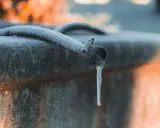 Un tuyau de jardin givré, avec une stalactite de glace tombant du robinet, illustre la nécessité de la protection tuyau en hiver.