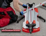 Un ouvrier en pantalon rouge utilise un coupe-carreaux professionnel pour ses travaux.