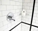 Un robinet de douche chromé et une étagère avec des serviettes sur un mur de carrelage blanc. Idéal pour nettoyer carrelage mural encrassé.