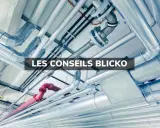 Un réseau complexe de tuyaux argentés et un tuyau rouge, installés au plafond. Ces tuyaux semblent cacher des secrets techniques.