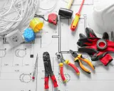Outils d'électricien et rouleau de câble pour radiateur électrique, prêts pour l'installation sur un plan.