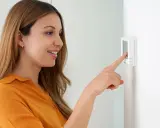 Une femme ajuste son cee thermostat connecté.