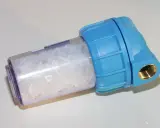 Filtre d'adoucisseur d'eau bleu rempli de cristaux blancs, peut-être une panne à résoudre.