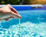 Main tenue une bandelette de test dans l'eau d'une piscine pour vérifier la qualité de l'eau, essentielle au bon fonctionnement du système pompe piscine.