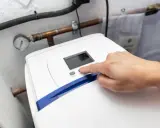 Main d'une personne appuyant sur le bouton "SET" d'un adoucisseur d'eau. Le manomètre indique la pression. Le 16 c'est quoi ?