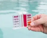 Testeur de piscine mesurant le chlore et le pH. La couleur rouge indique un niveau de chlore élevé, suggérant qu'il faut enlever le chlore de l'eau.