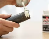 Application de pâte sur le filetage d'un **tube pour joint**. Un pot de pâte est visible à droite.