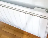 Radiateur électrique blanc installé sur un parquet. Un écran affiche la température. Guide pour comment installer un radiateur électrique.