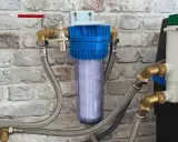 Système de filtration d'eau avec cartouche visible, raccordé à un adoucisseur. Un filtre avant adoucisseur obligatoire pour une eau pure.