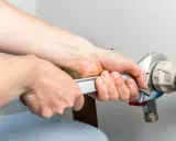 Mains d'un technicien serrant un raccord de tuyau lors d'un entretien adoucisseur d'eau Culligan.