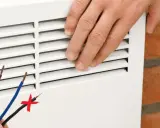 Installation d'un radiateur électrique. Les fils dénudés suggèrent une connexion, mais le fil noir barré indique une erreur. Le pilotage radiateur électrique sans fil pilote est la solution.