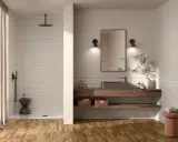 Une **salle de bain moderne** avec un sol en bois, une douche à l'italienne, un lavabo suspendu et un miroir.
