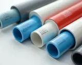 Plusieurs tuyaux en plastique de différentes couleurs (bleu, blanc, rouge, gris) sont alignés, certains emboîtés.