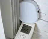 Schéma branchement thermostat chauffage électrique : un boîtier blanc "heatzy" et une télécommande affichant 19.0°C, près d'un radiateur.