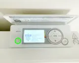 Thermostat sur radiateur électrique. L'écran affiche "MODE AUTO" pour un pilotage intelligent. Le bouton d'alimentation est allumé en vert.