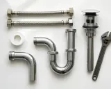 Ensemble de plomberie chromé : tuyaux flexibles, siphon, bonde et clé. Prêt pour un raccord SMS parfait.