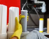 Mains de gant jaune manipulant un filtre pour le nettoyage résine adoucisseur d'eau.