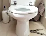 Préparez-vous à changer l'abattant WC. Nettoyants, serviette et pince à portée de main pour le bricolage.