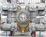 Gros équipement industriel gris avec des tuyaux orange, un ventilateur central et des éléments circulaires. Il s'agit d'un joint SMS, prêt pour l'assemblage.