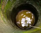 Puits profond avec eau trouble, une corde et un seau pour aider à éliminer le fer dans l'eau de forage.