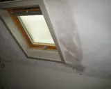 Gouttes d'eau sur le mur d'une maison non chauffée, près d'une fenêtre de toit. La condensation s'accumule et coule.