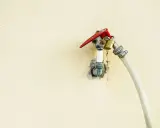 Robinet extérieur avec un cadenas doré et un tuyau blanc, le raccord asymétrique suggère une utilisation inhabituelle.