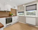 Cuisine moderne avec placards blancs, plan de travail en bois et un radiateur blanc discret assurant le chauffage.